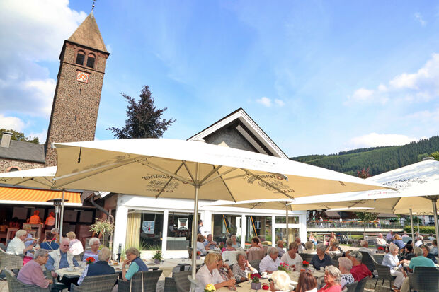 Im Schatten der katholische St.-Jodokus-Kirche – einem denkmalgeschützten Gotteshaus – befindet sich das Landhotel Voss, dessen große Terrasse mit Außengastronomie direkt bis an den "Lenne-Strand" reicht. Hier lässt es sich an heißen Tagen gemütlich bei Kaltgetränken oder Kaffee und Kuchen verweilen. FOTO: ANDREAS DUNKER