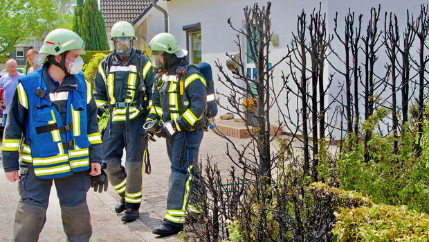Feuerwehrleute untersuchten die Brandstelle noch auf mögliche Glutnester. Anwohner hatten die lichterloh brennende Lebensbaumhecke aber bereits zuvor gelöscht. FOTO: ANDREAS DUNKER