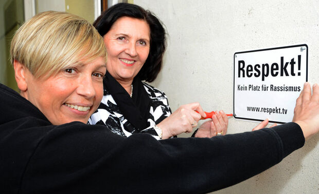 Schilder an Kreis-Immobilien machen deutlich: Hier ist kein Platz für Rassismus. – Hier ein Archivbild mit der Ex-Fußballnationalspielerin Sandra Minnert und Landrätin Eva Irrgang (CDU) beim Anbringen des Schildes „Respekt! Kein Platz für Rassismus“ am Haupteingang der Kreisverwaltung in Soest vor einiger Zeit. In Wimbern hängt ein vergleichbares Schild am NEF-Standort. ARCHIVFOTO: JUDITH WEDDERWILLE / KREIS SOEST