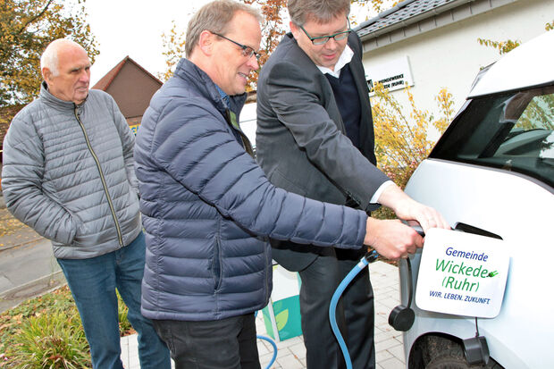 Bürgermeister Dr. Martin Michalzik (CDU) sowie Aufsichtsratsvorsitzender Hans Regenhardt (CDU) und Geschäftsführer Michael Lorke von den Gemeindewerken Wickede (Ruhr) beim "Betanken" des neuen Elektrofahrzeugs der Kommune. FOTO: ANDREAS DUNKER