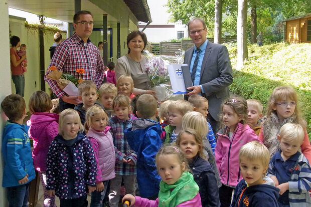 Silbernes Dienstjubiläum: Marita Poliwoda, Leiterin des kommunalen Regenbogen-Kindergartens in Wiehagen, mit Bürgermeister Dr. Martin Michalzik (rechts) und Personalratsvertreter Daniel Luig (links) sowie "ihren" Kindern FOTO: GEMEINDE WICKEDE (RUHR)