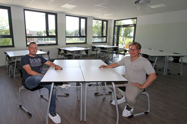 Kurze Verschnaufpause für Bauleiter Sebastian Gratzfeld (links) und Projektleiter Simon Bellenhaus (rechts) in einem der möblierten Klassenzimmer. Ansonsten ist für die Mitarbeiter des Generalbauunternehmers Kleusberg derzeit Endspurt angesagt. FOTO: ANDREAS DUNKER
