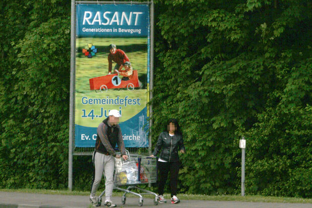 Auf dem Weg von Wickede nach Wimbern: Ein Flüchtlingspaar schiebt am heutigen Mittwochabend (3. Juni 2015) gemütlich einen ALDI-Einkaufswagen vor sich her. Im Hintergrund das Werbebanner zum evangelischen Gemeindefest mit der Aufschrift "RASANT – Generationen in Bewegung". FOTO: ANDREAS DUNKER